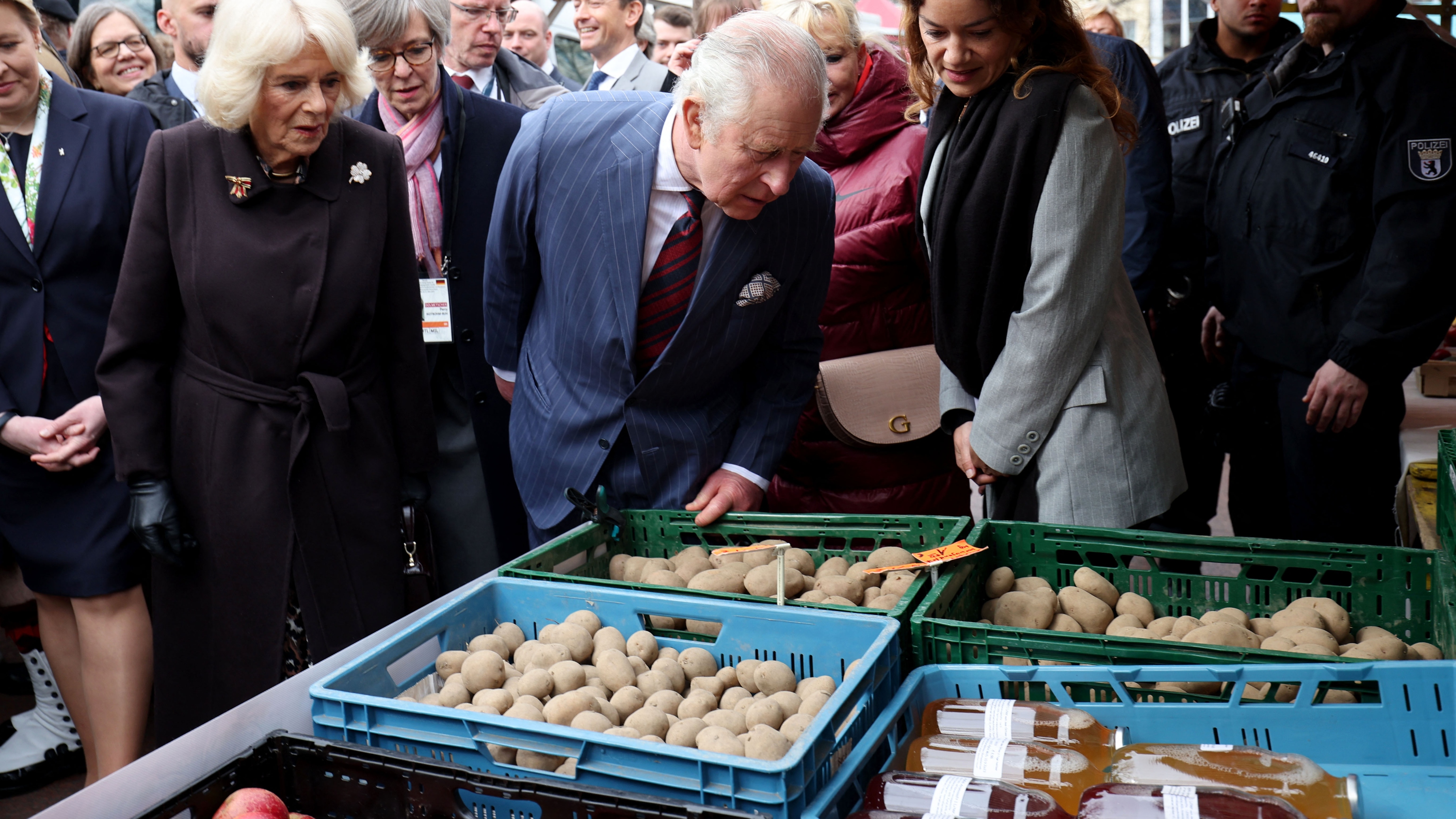 King Charles III (C) and Queen Camilla (2nd L) look at potatoes as they visit a food market on Wittenbergplatz in Berlin, on March 30, 2023