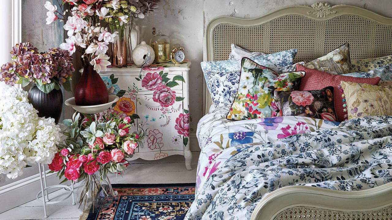 Women&#039;s bedroom with bouquets of flowers, printed floral duvet and painted white drawers by Homesense