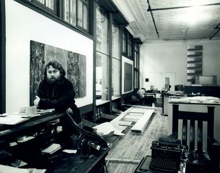 A black & white photo of Donald Judd. He's in his studio.