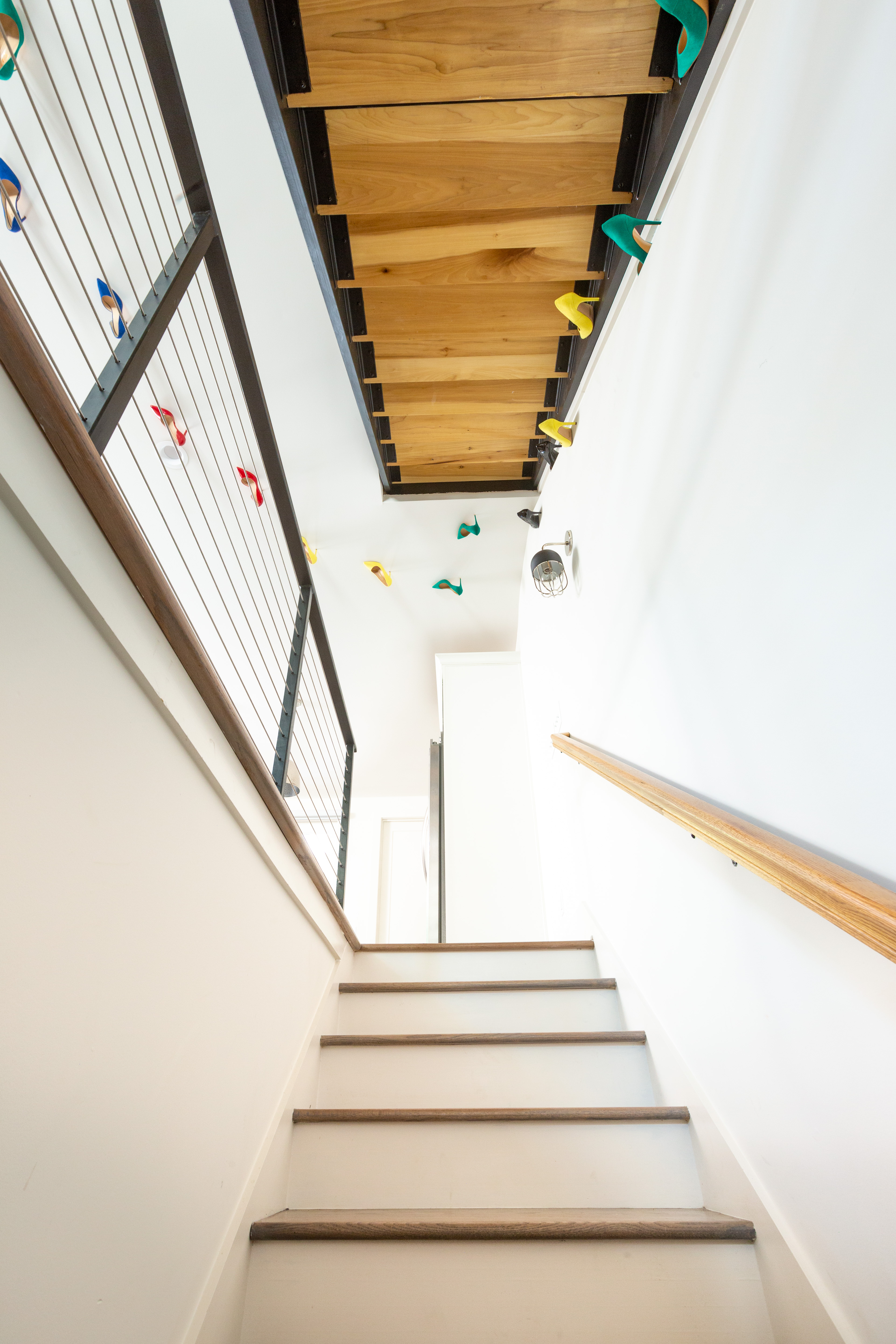 View up staircase with bright shoes used as artwork on walls