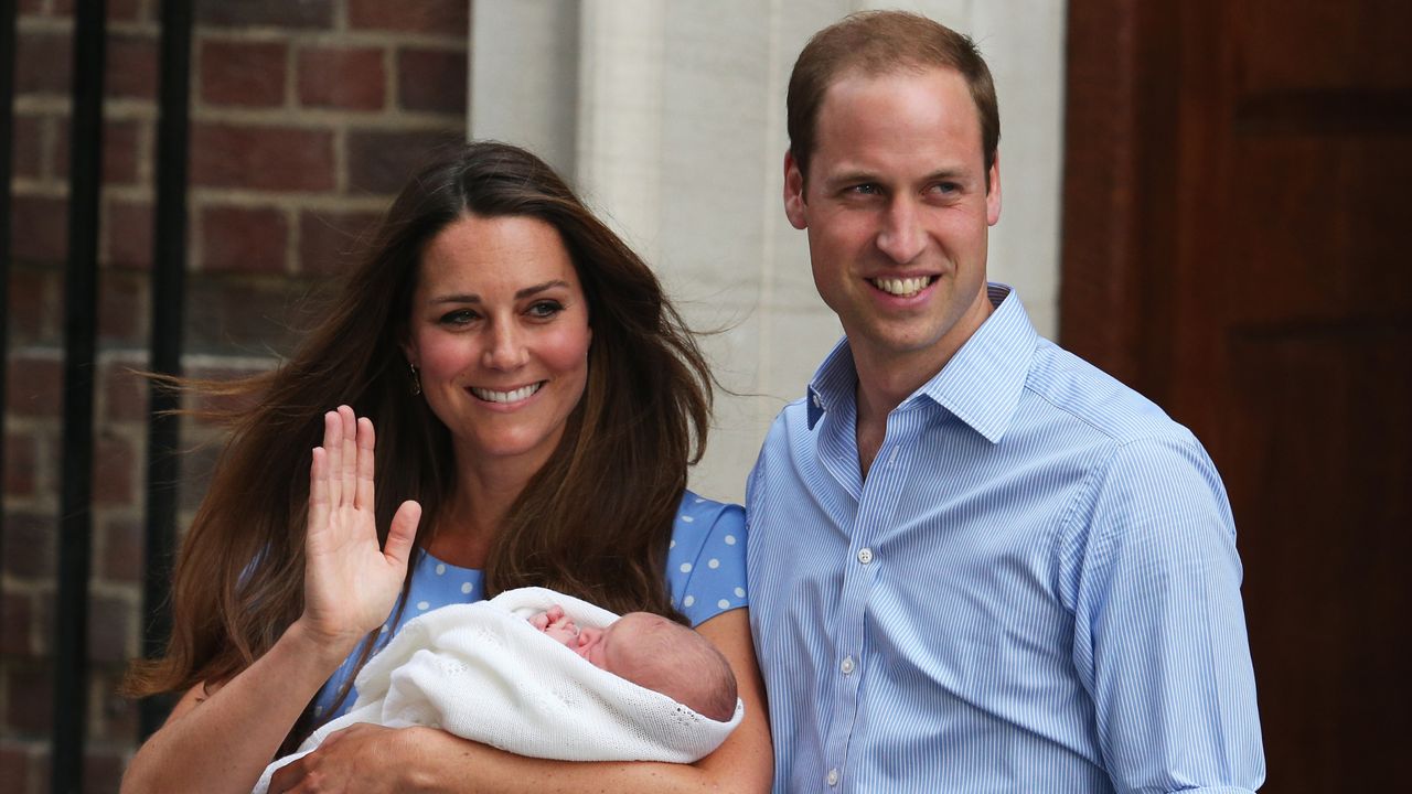 Princess Kate and Prince William standing outside the hospital holding Prince George wrapped in a white blanket