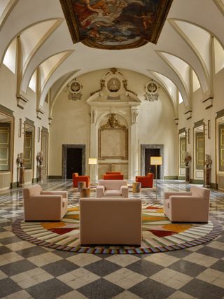 A hotel room sited within an ancient palazzo juxtaposes modern colorful furniture with frescoed walls and vaults.