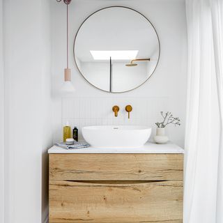 Bathroom with white walls, wooden washstand and round mirror