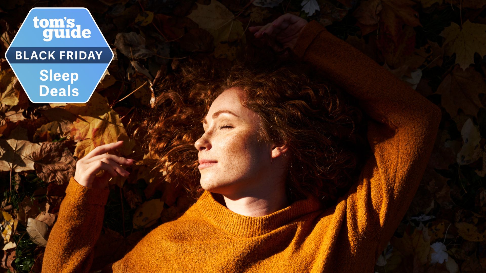 A woman lying on autumn leaves sleeping and smiling