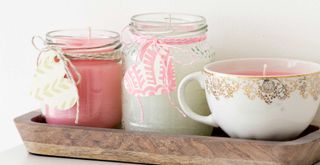 Homemade candles in tea cup and jars to suggest how to make your home smell good