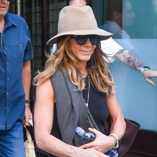 Jennifer Aniston wearing a tan hat, black tank top, khaki denim, and flip-flops at the Greenwich Hotel in Tribeca, New York. 