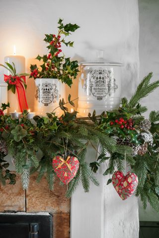 Decorated mantlepiece with a foliage garland, holly and candles