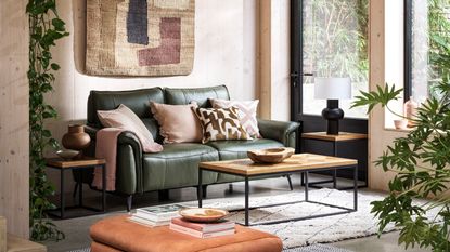 Neutral living room with compact green leather sofa and a textural wall hanging above it