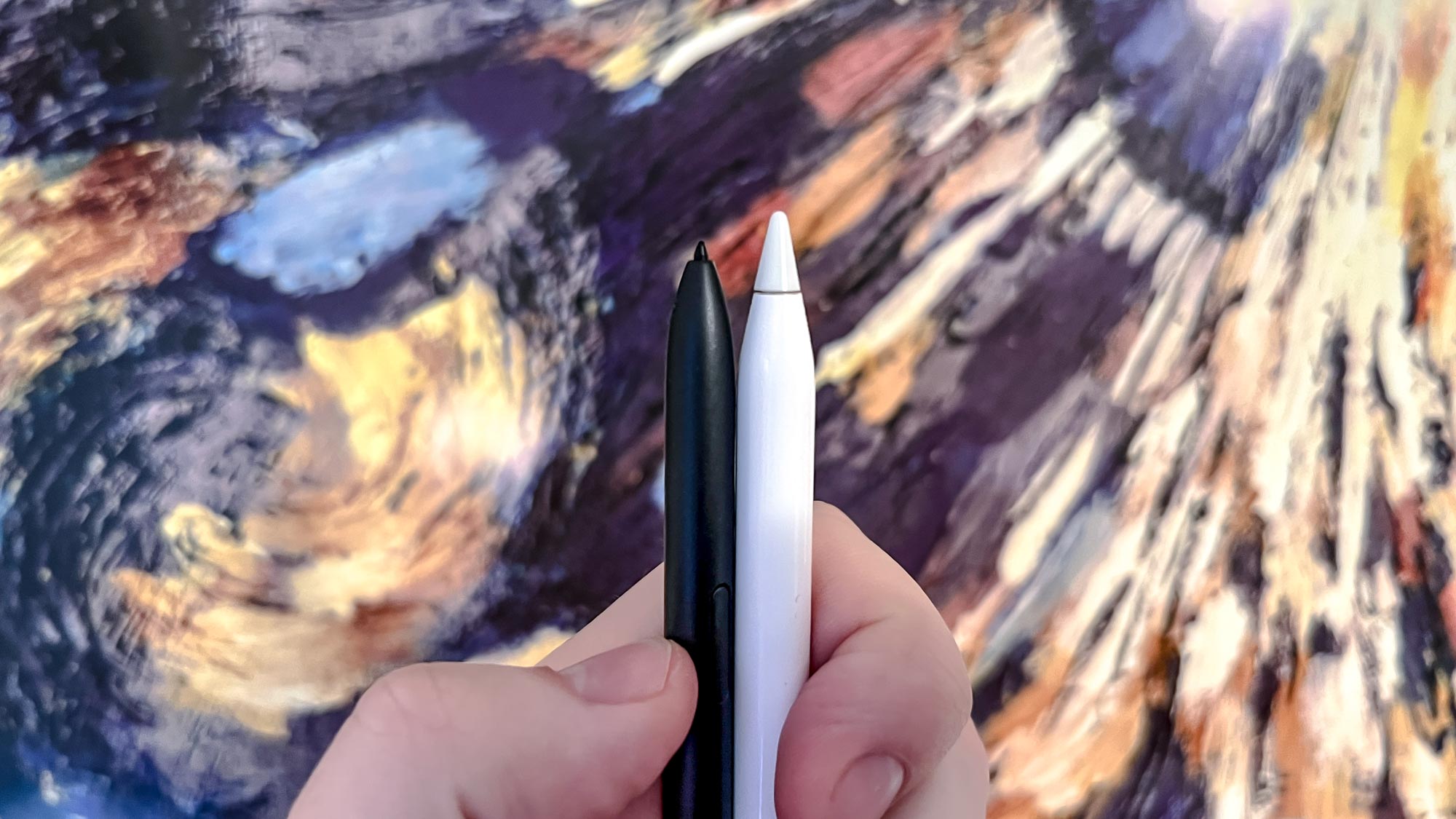 A Samsung S Pen and an Apple Pencil, put together in front of a poster