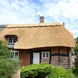 thatched cottage with brick wall white door and window