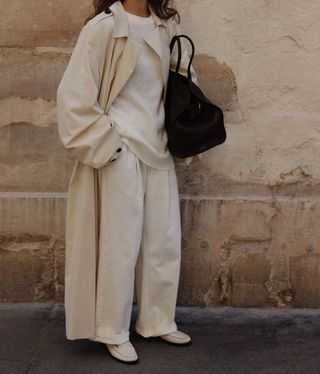 @modedamour wears cream loafers with tonal tailored trousers, a knitted jumper and trench coat.