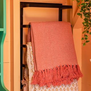 orange painted beach hut with towel rack and blankets