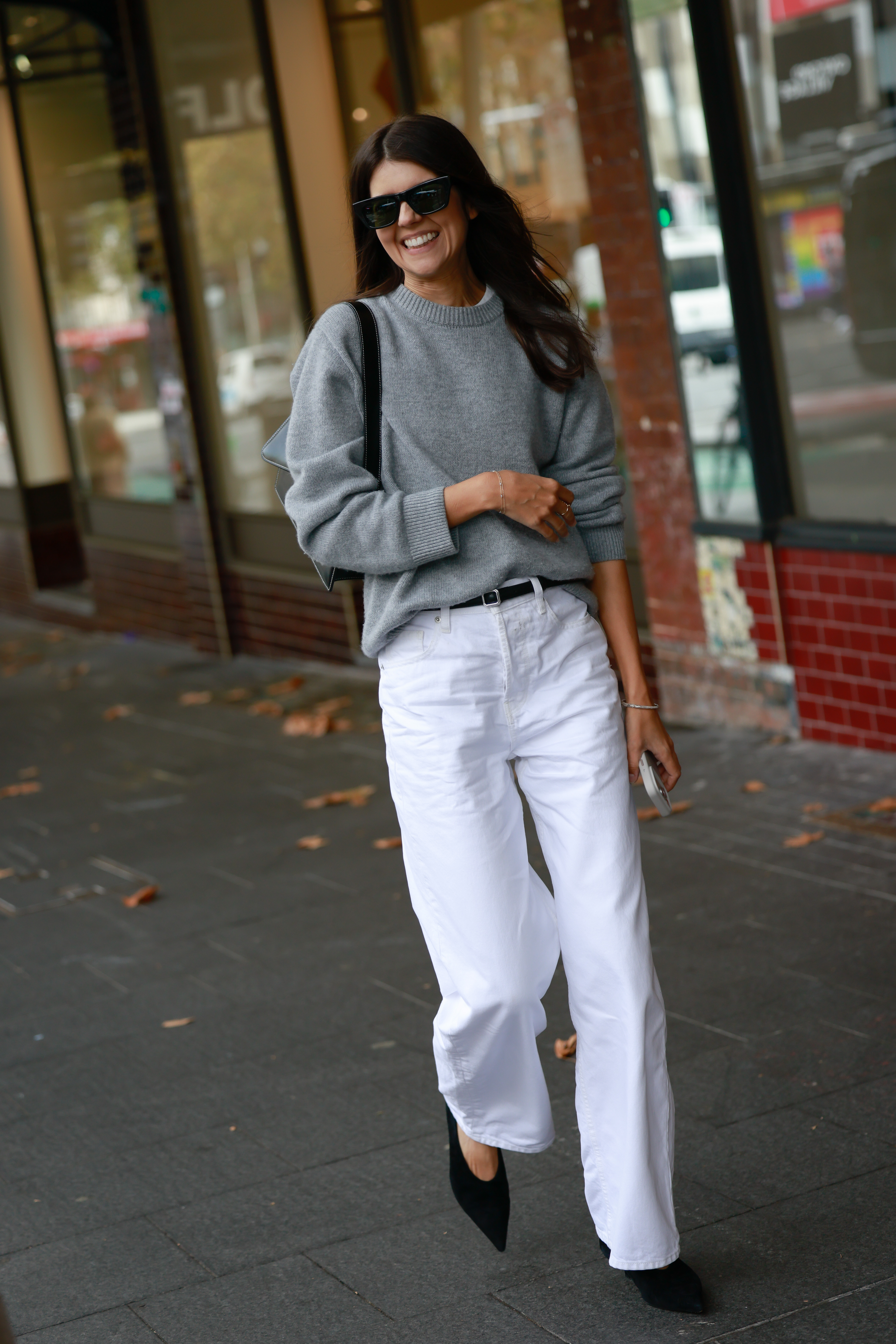 SYDNEY, AUSTRALIA - MAY 13: A guest wearing black sunglasses, grey jumper, white pants and black heels outside the NAGNATA show at Australian Fashion Week 2026 on May 13, 2026 in Sydney, Australia. (Photo by Hanna Lassen/Getty Images)