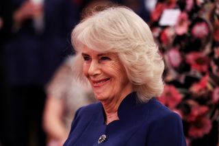 Queen Camilla wearing a blue coat and smiling