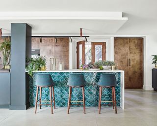 Family kitchen with large island and bar stools upholstered in teal fabric