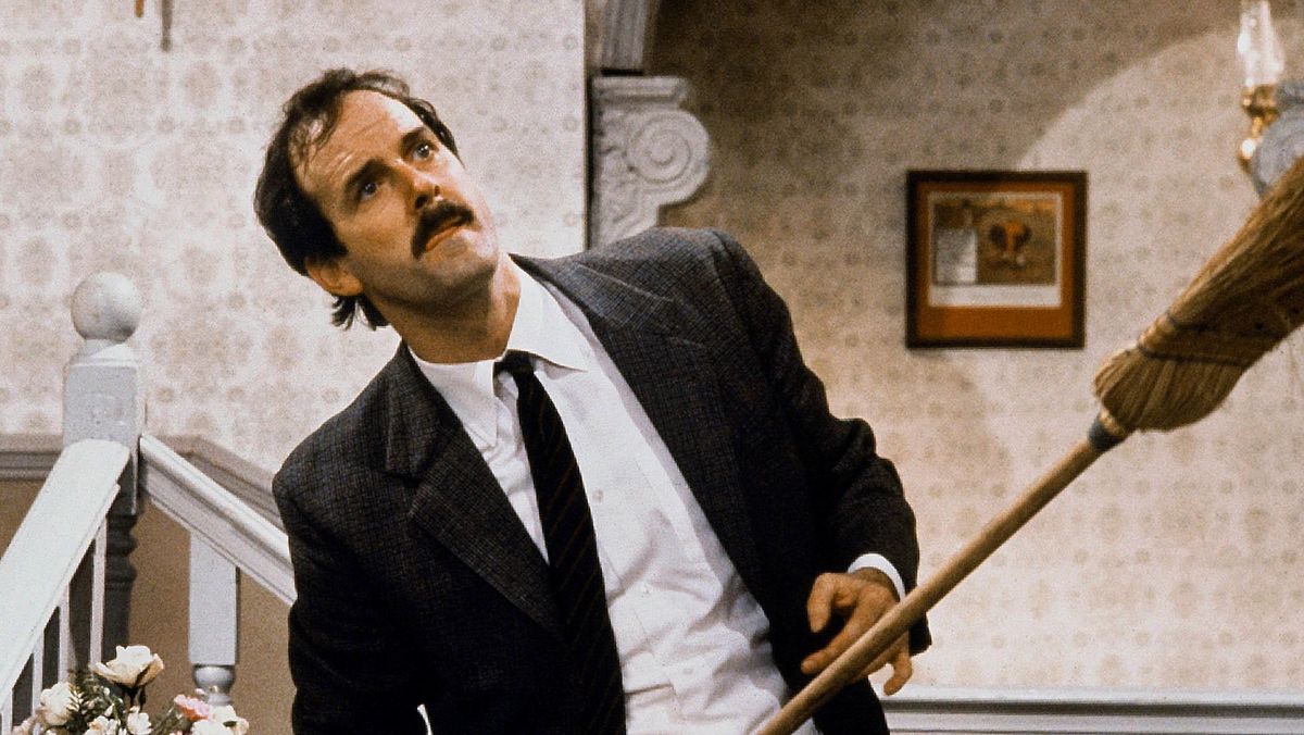 John Cleese holding a broomstick in Fawlty Towers