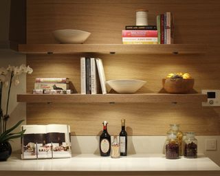 Undercupboard lights In kitchen with white Orchid flower decor, recipe books, bowls and ingredients in glass jars