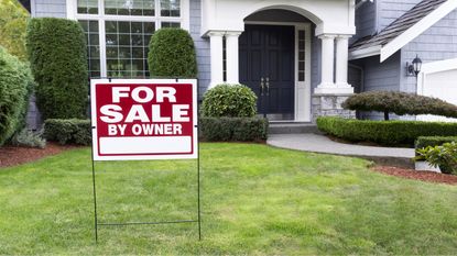 A "for sale by owner" sign in the yard of a home.