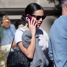 Olivia Rodrigo wearing a gray cardigan, white T-shirt, plaid skirt, socks, woven leather bag, and Mary Janes