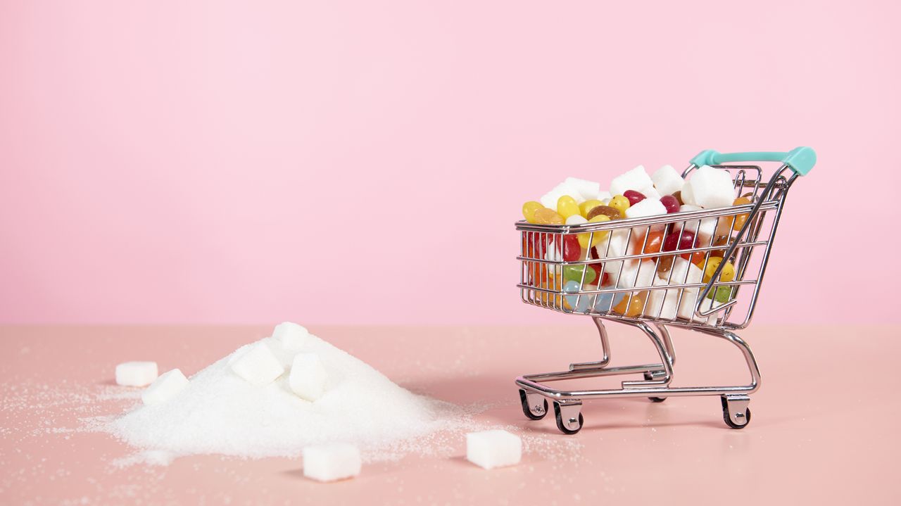 Supermarket trolley with candy next to pile of sugar