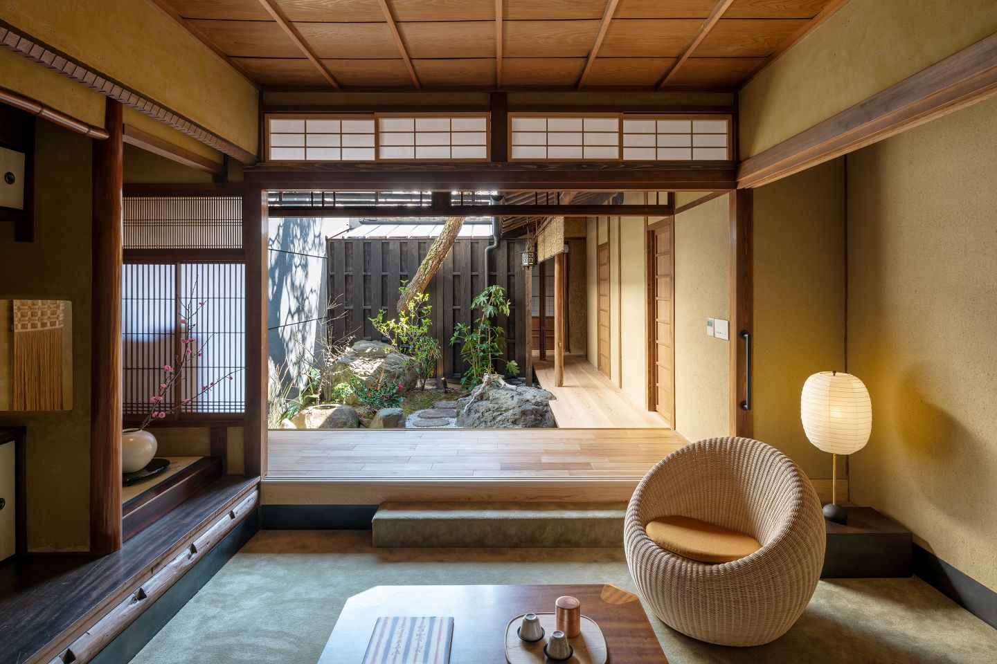 The warm, welcoming interiors of a traditional Japanese inn, with layered textiles, wood marquetry, and paper lanterns.