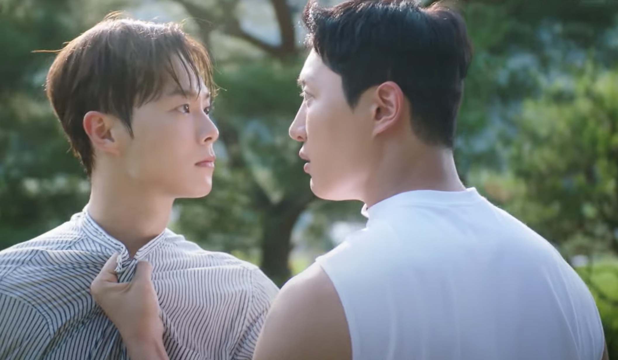 one man tugs on another man's shirt while outdoors on a farm in a still from the bl kdrama love tractor