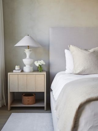 minimalist bedroom corner with oak bedside table, white lamp and whitewash walls