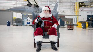 Santa Claus sits ready for flight in front of an F-16 at Buckley Air Force Base.