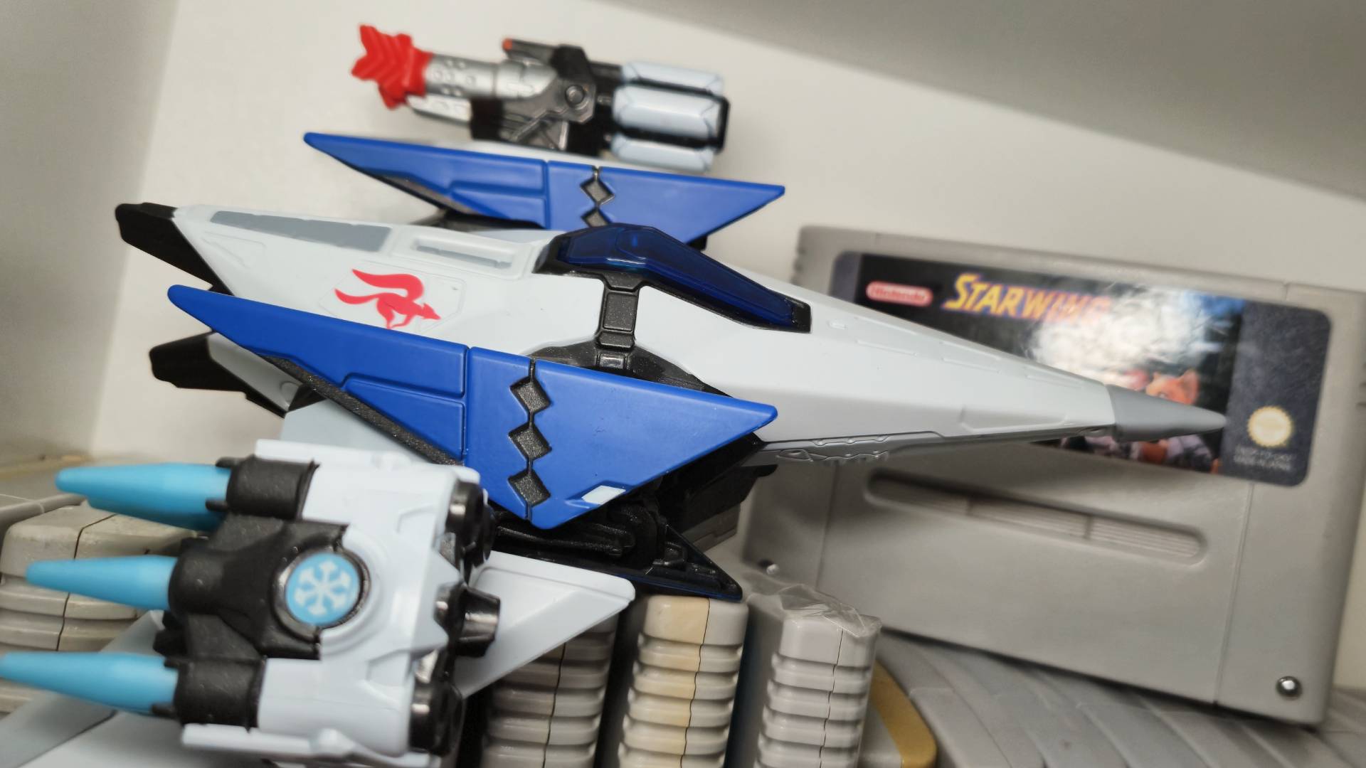 Photo of the Arwing from Battle for Atlas sitting on a pile of SNES games.