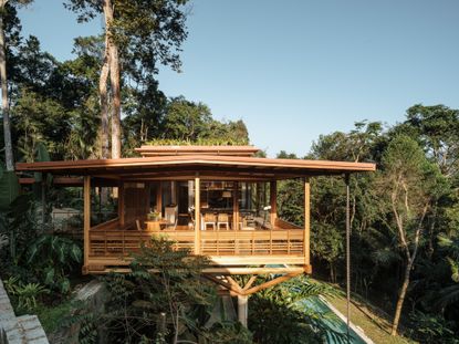 casa quinta by arquipelago in brazil, a wooden home floating above the tropical rainforest