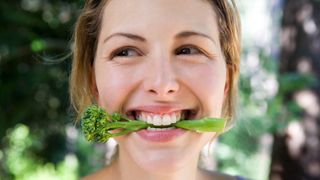 Woman biting into broccoli