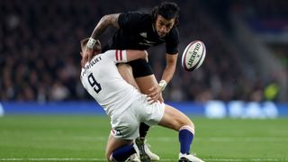 An England player tackles an All Black chasing the ball during New Zealand vs England rugby.