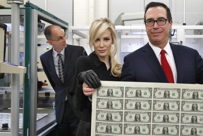 Treasury Secretary Steven Mnuchin, right, and his wife Louise Linton, hold up a sheet of new $1 bills, the first currency notes bearing his and U.S. Treasurer Jovita Carranza's signatures, We