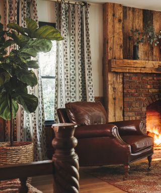 living room with wood and brick fireplace, patterned curtains and leather armchair