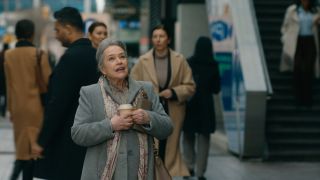 Kathy Bates mira hacia arriba con asombro mientras sostiene una taza de café afuera en Matlock.