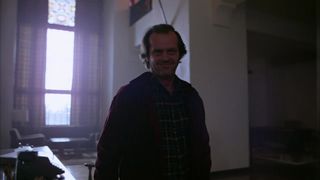 Jack Nicholson standing in a hotel room with a typewriter behind him