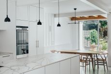 white kitchen with marble backsplash and oak table and chairs