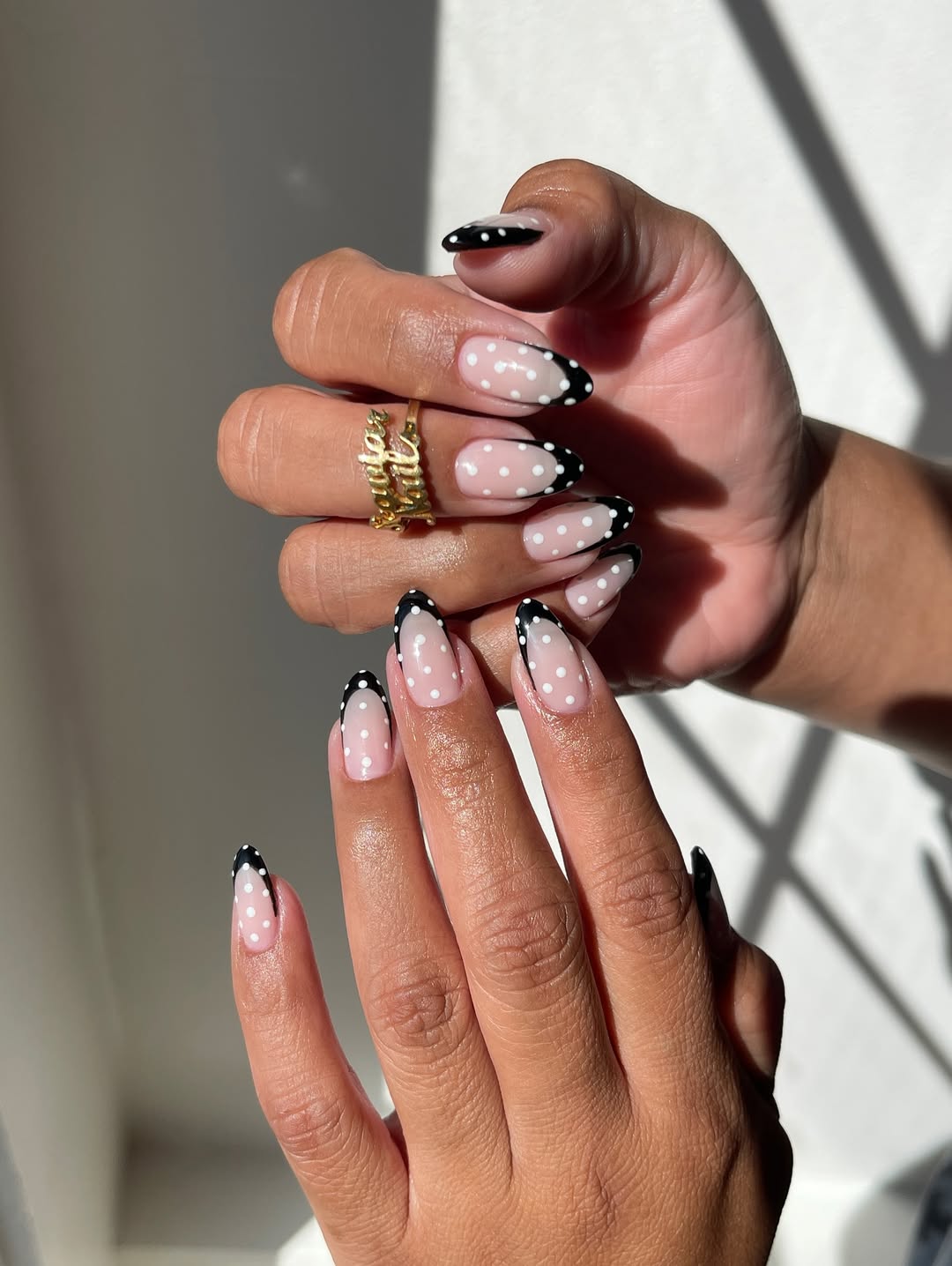 a black french manicure with white polka dots on top