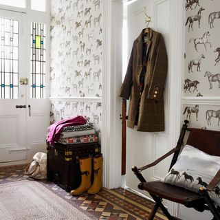 hallway with horse print wallpaper and hanging coat