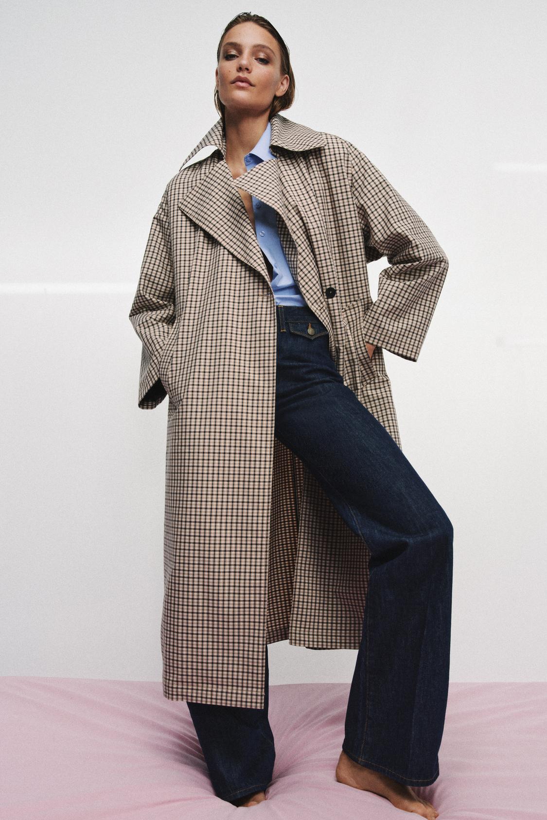 Model wears blue shirt, indigo jeans and checked trench coat