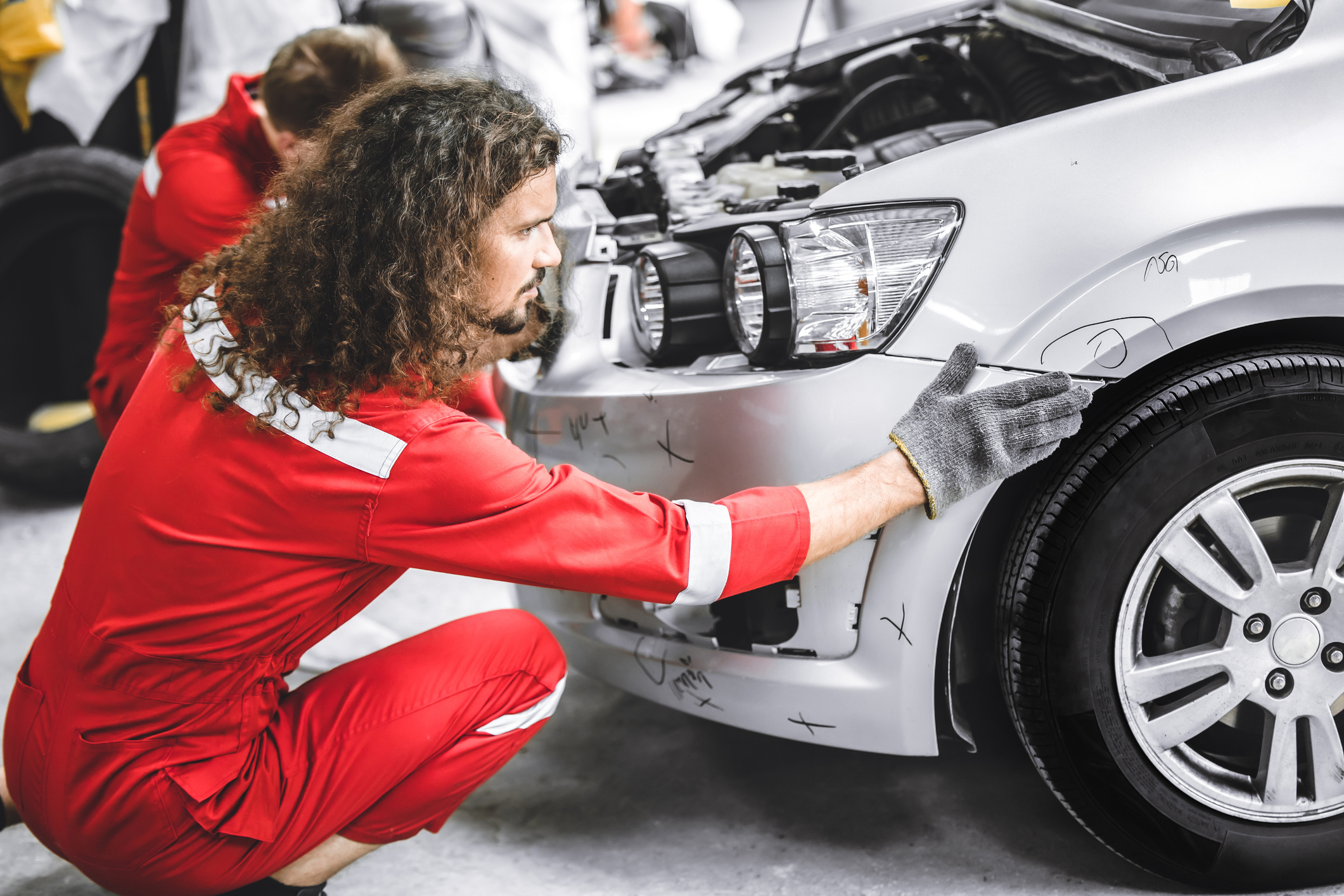 Mechanics repair the front bumper of a car after a car accident.