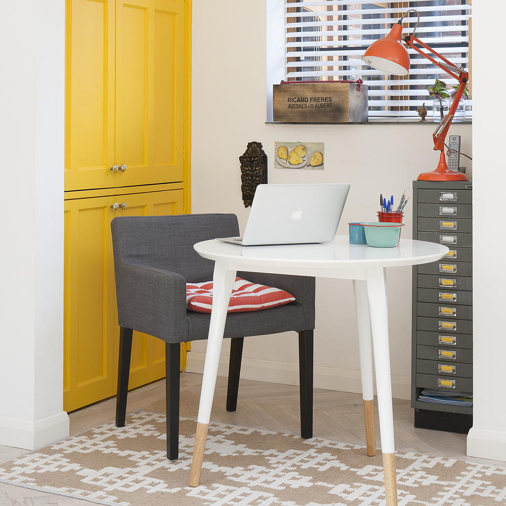 room with armchair white table and yellow cupboards