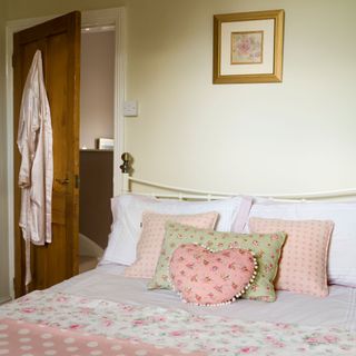bedroom with floral and polka dot bed linen and spot cushions and throw