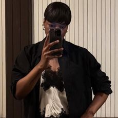 A woman wears a ivory silk blouse with black lace trim and a black coat.