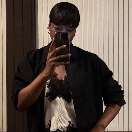 A woman wears a ivory silk blouse with black lace trim and a black coat.