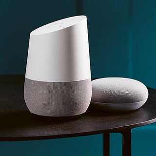 blue wall room with white and silver google assistant speakers on black table