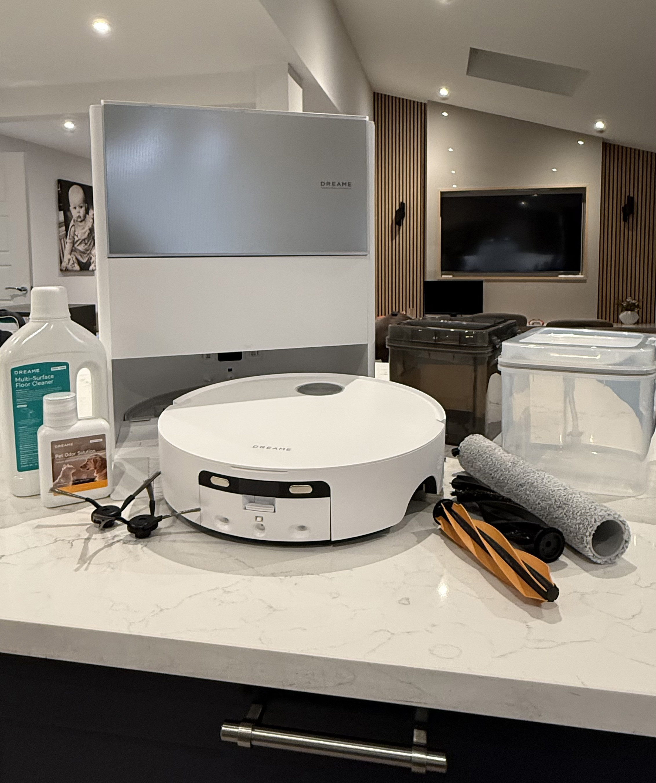 Dreame Aqua10 Ultra Roller displayed with spare brushes, roller mop, water tanks, and cleaning solutions on a countertop