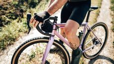 A cyclists sits aboard a gravel bike on a gravel trail