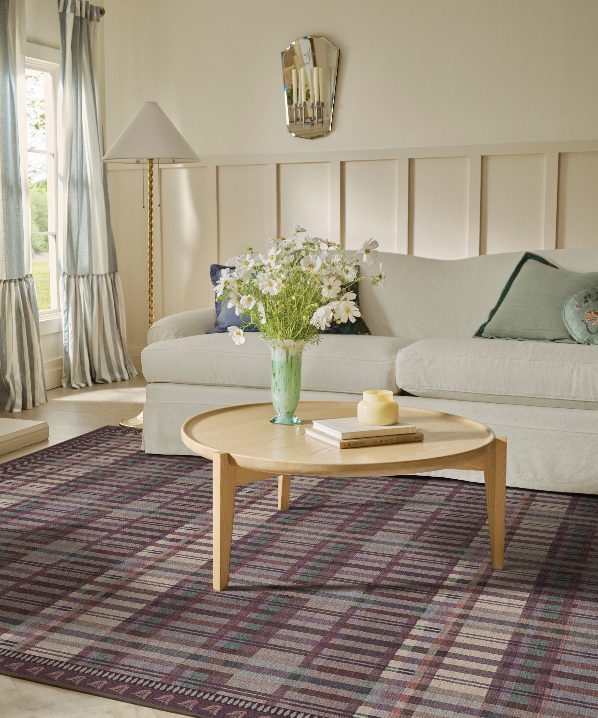 a living room with a purple plaid rug, a wooden coffee table, and a cream sofa with throw pillows
