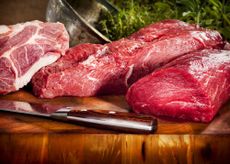 Raw meat sits on a cutting board.